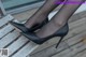 A close up of a woman's legs wearing black shoes.