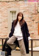 A woman leaning against a railing in front of a brick building.