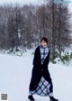 A woman standing in the snow wearing a blue coat.