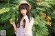 A woman in a straw hat standing in front of a bush.