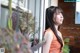 A woman in an orange dress leaning against a window.