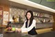 A woman standing behind a counter holding a plate of fruit.