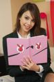 A woman in a business suit holding a pink book.