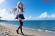 A woman in a school uniform walking on the beach.